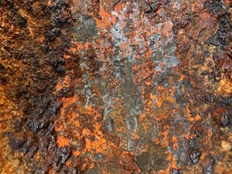 Rusted steel beside a cleaned test patch